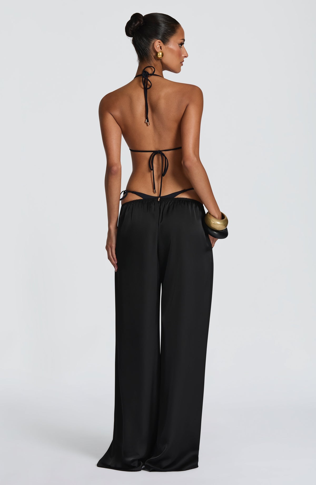 Pantalón negro de pierna ancha, vista trasera; cintura con cordones ajustables.