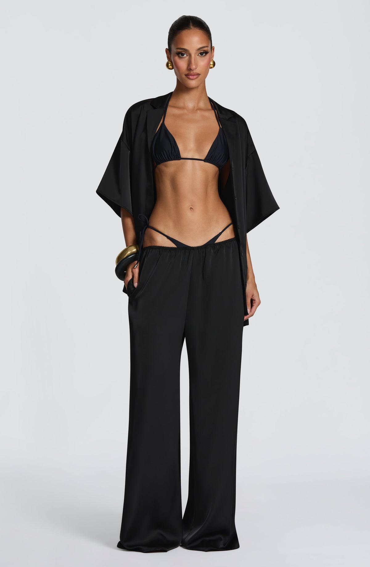 Pantalón negro de pierna ancha, cintura fruncida con cordones ajustables.