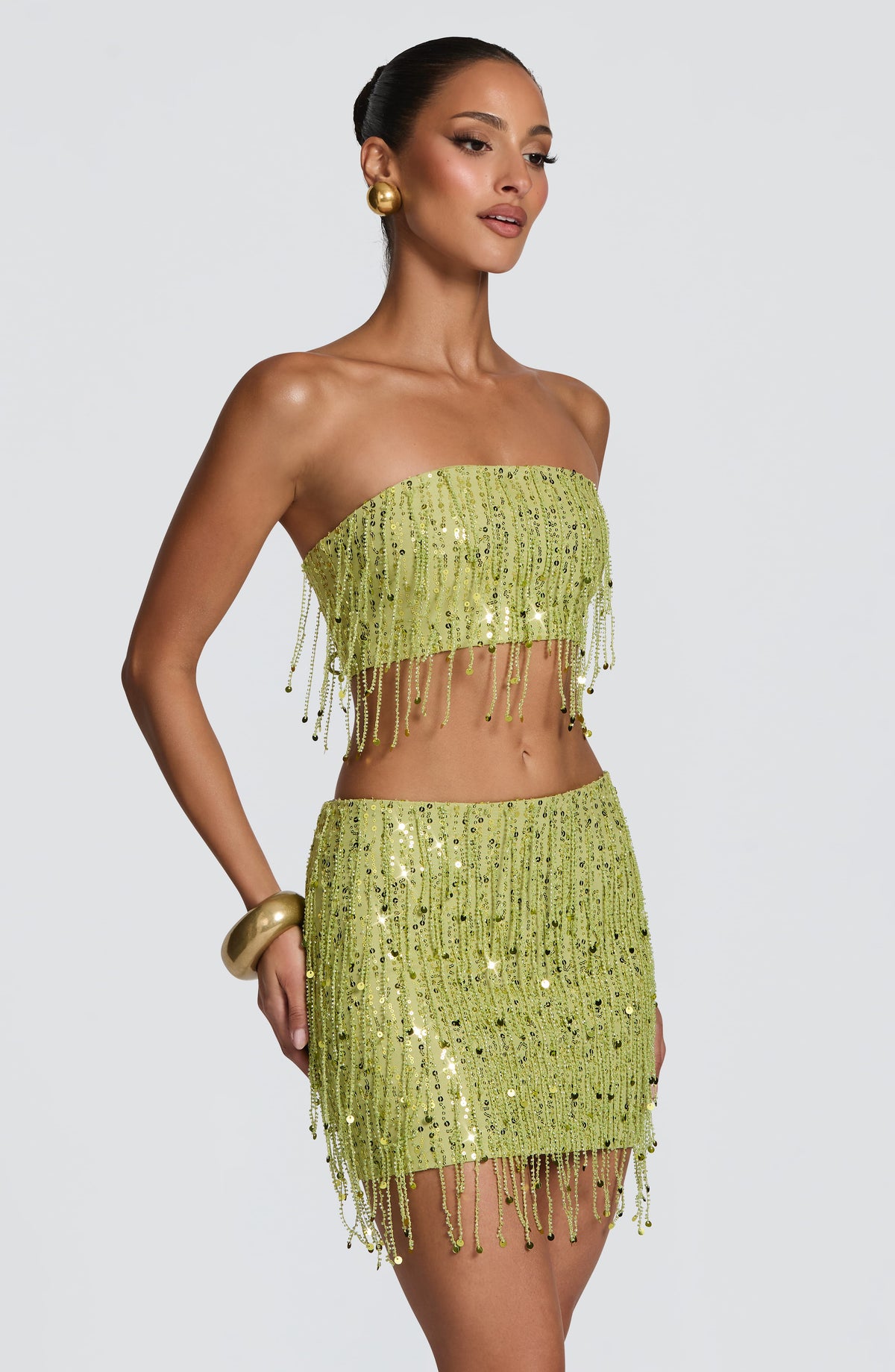 Mini falda verde oliva con lentejuelas y flecos, borde con caída asimétrica