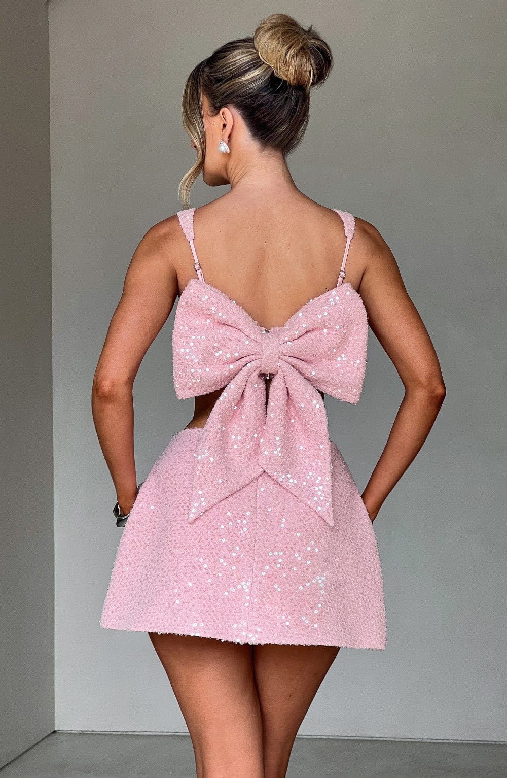 Minifalda rosa con lentejuelas y lazo grande trasero en la espalda con tirantes finos