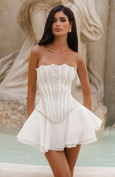 Vestido corto marfil tipo corsé bandeau con falda acampanada y volantes