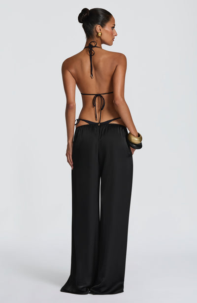 Pantalón negro de pierna ancha, vista trasera; cintura con cordones ajustables.