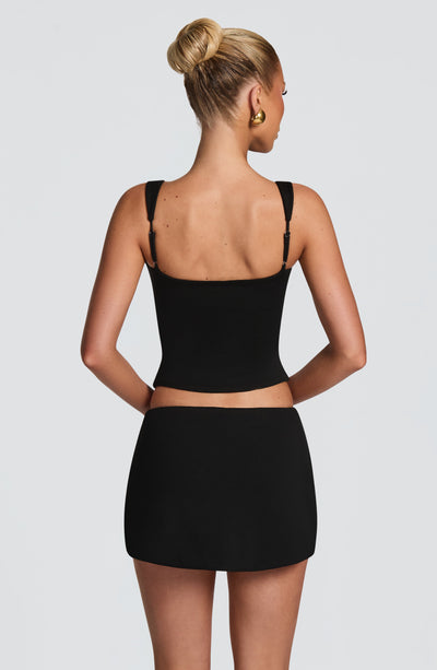 Falda-pantalón negra con diseño trasero liso, tirantes de hombro y corte corto.
