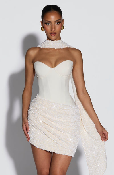 Vestido blanco sin mangas con escote corazón y franja brillante sobre la falda corta.
