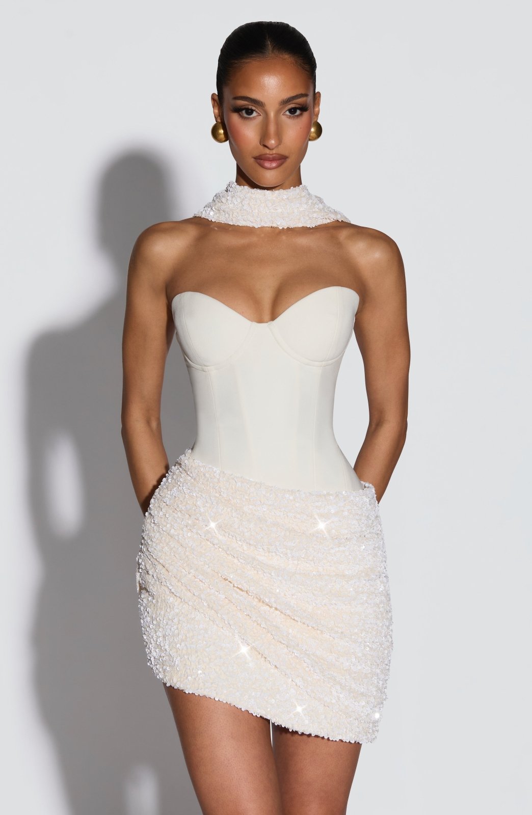 Vestido blanco sin mangas con escote corazón alto y falda corta de pedrería.