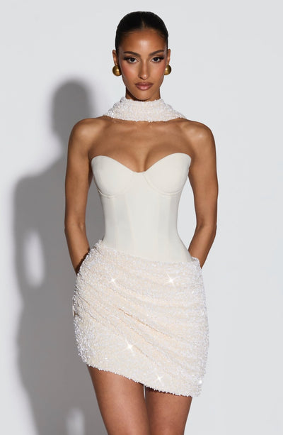 Vestido blanco sin mangas con escote corazón alto y falda corta de pedrería.