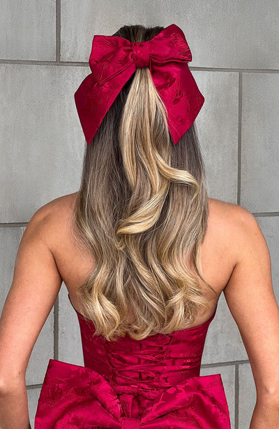 Lazo de cabello rojo tipo moño grande con textura, sujetado al pelo