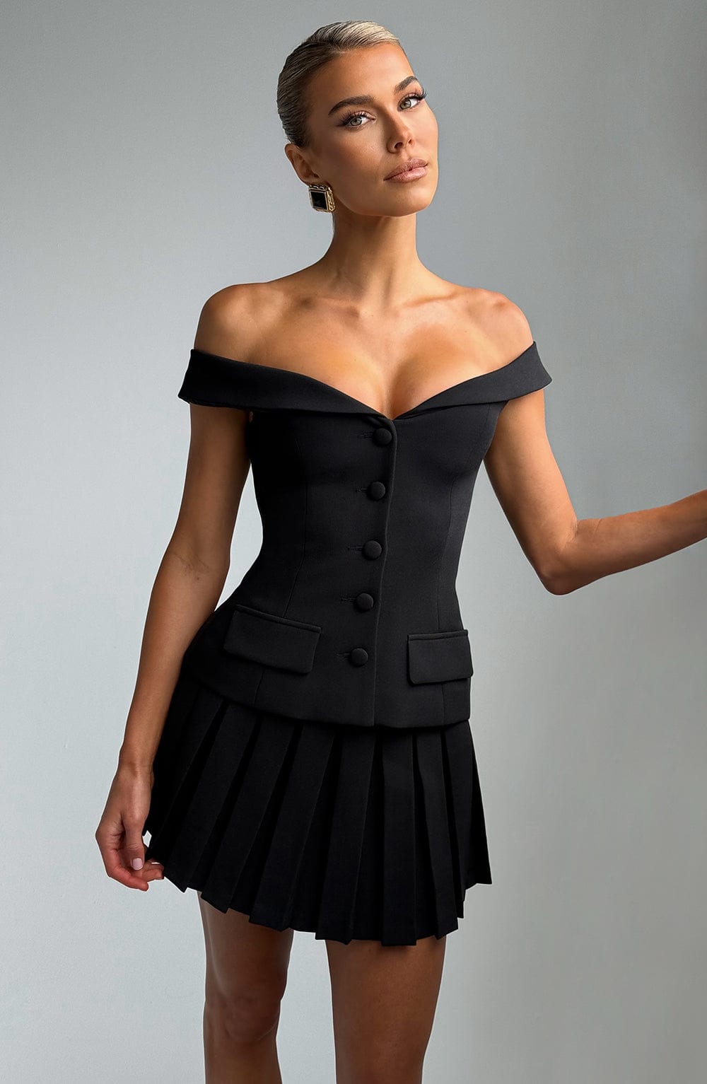 Minifalda negra plisada con vuelo y cintura entallada, estilo corsé.