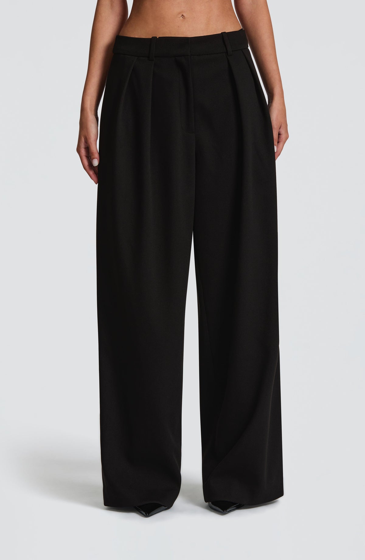 Pantalón negro de pierna ancha con cinturilla lisa y pliegues frontales
