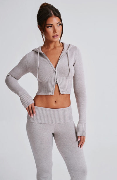 Conjunto de sudadera con cremallera y capucha gris claro; pantalón a juego.