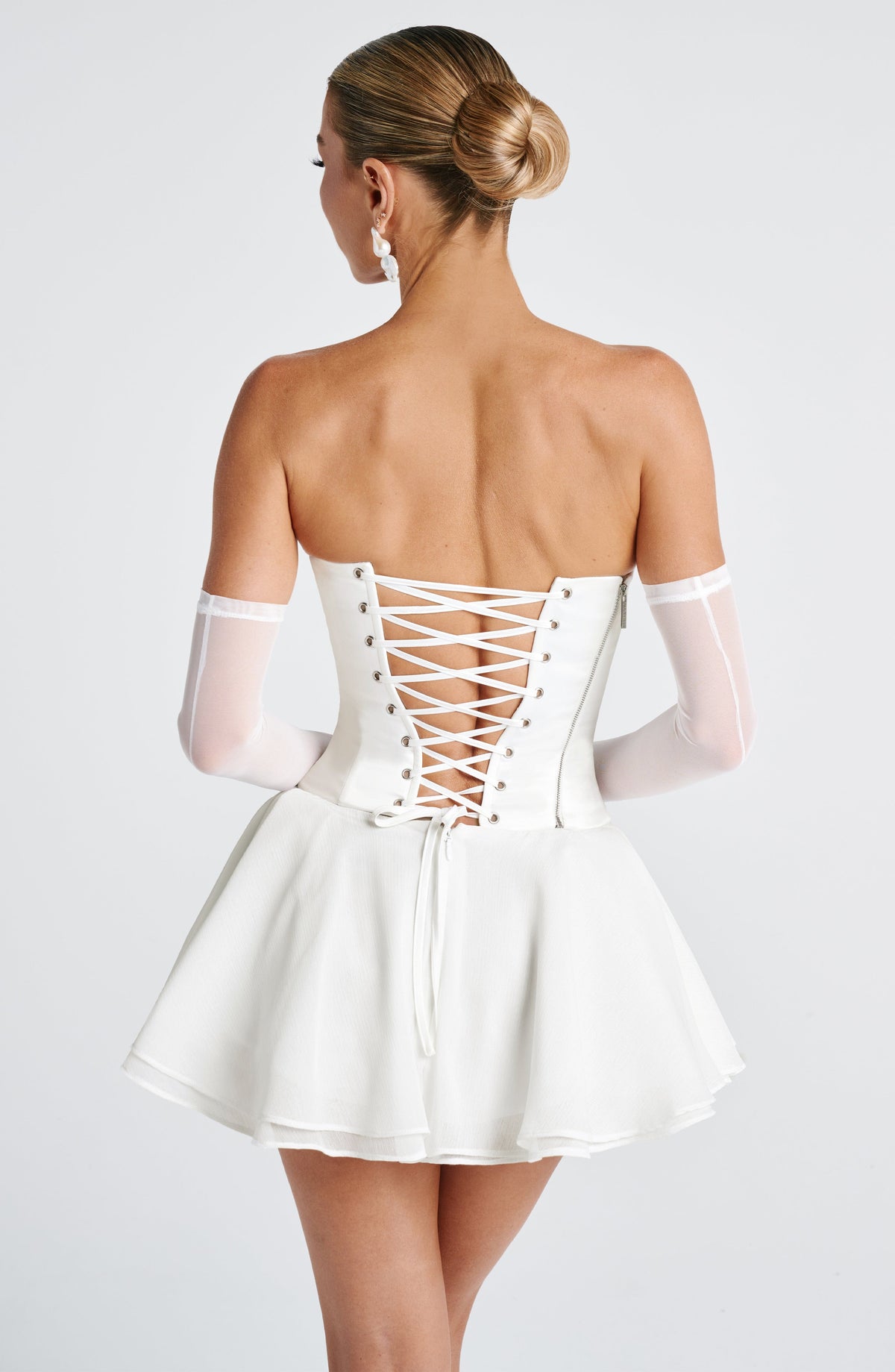 Vestido corto marfil con espalda cruzada de cordones y falda acampanada con volantes