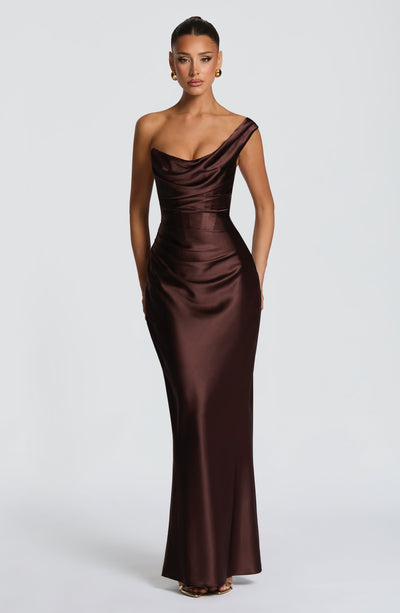Vestido largo satinado marrón oscuro con drapeado, escote asimétrico y corte entallado.