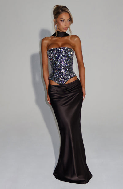 Corsé negro strapless con pedrería y falda satén larga negra, vista de cuerpo completo.